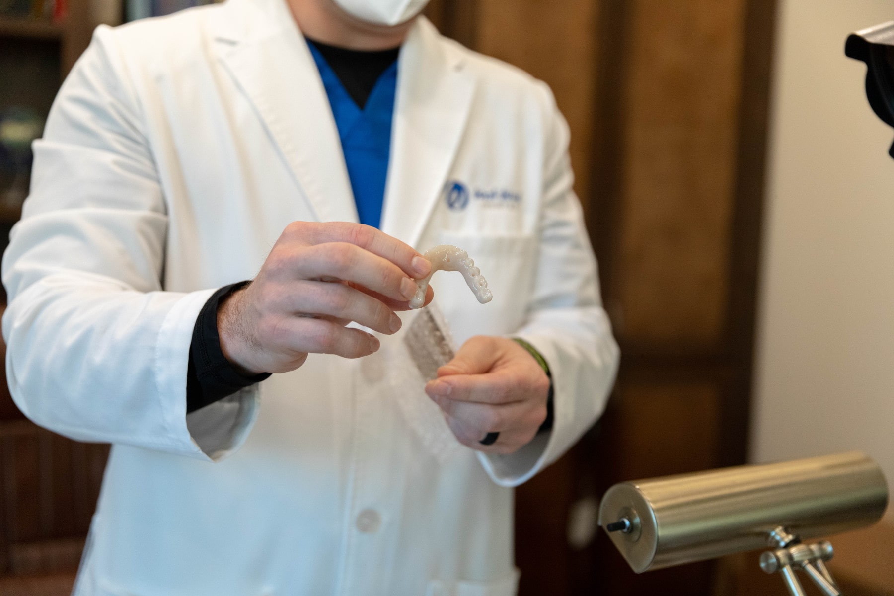 A dentist shows off a custom set of fixed dentures.